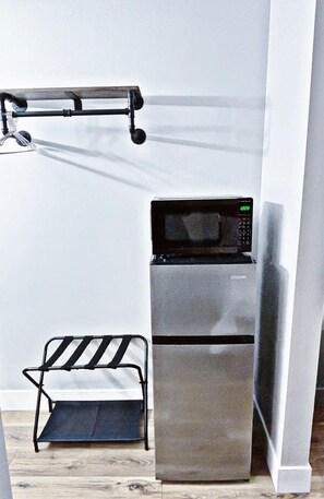 Une petite cuisine équipée d’un four à micro-ondes, d’un petit évier et d’un étendoir à linge en métal.