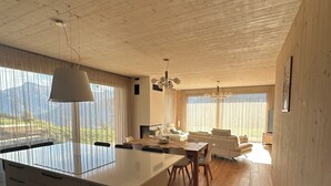 Una cocina moderna con una isla central, techo de madera y ventanas amplias con cortinas livianas.