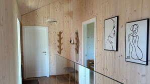 Un interior de madera con una escalera, una puerta y dos obras de arte enmarcadas en la pared.