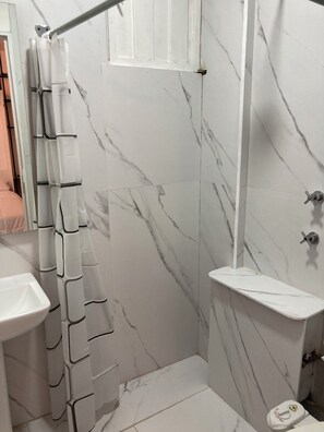 Een douche, handdoeken, zeep, toiletpapier