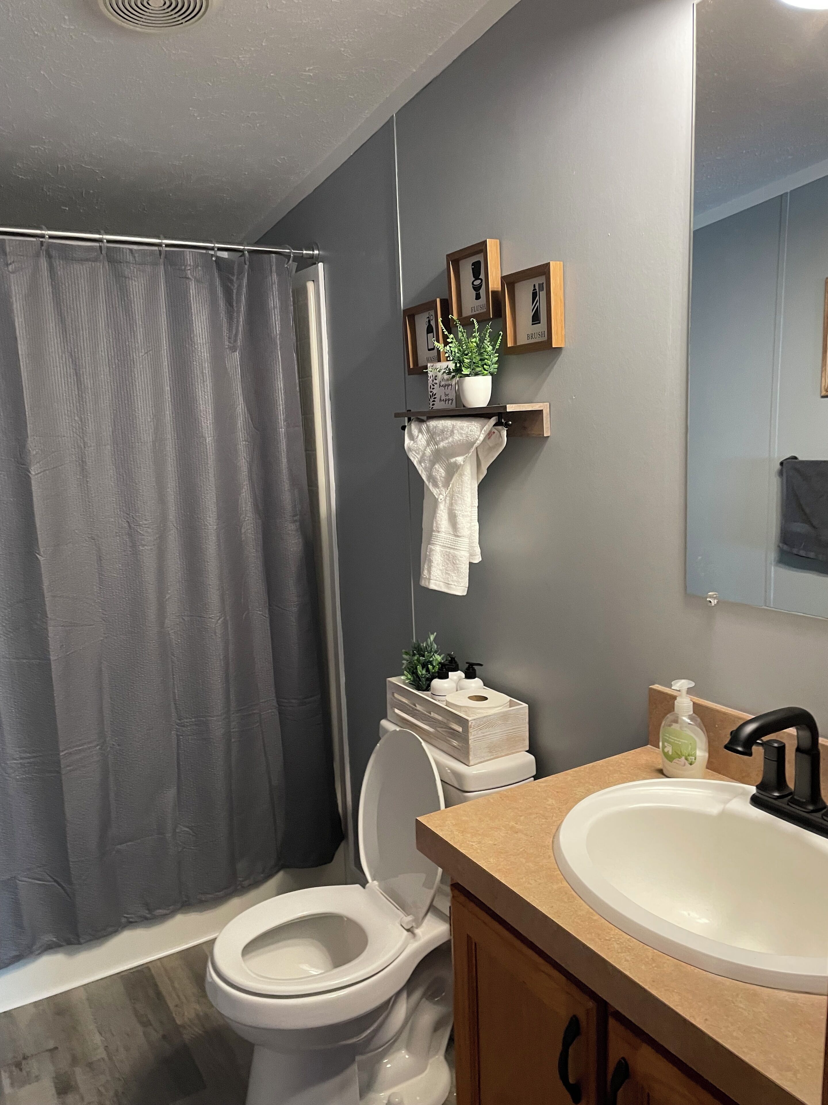 Een badkamer met toilet, wastafel, douchegordijn en een plank met toiletartikelen.