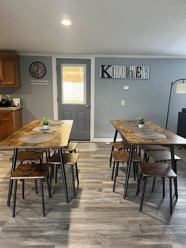 A dining area with two wooden tables, benches, and a clock on the wall.