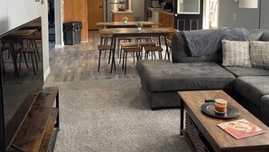 A modern living room with a grey sectional sofa, a wooden coffee table, and a dining area with a wooden table and chairs. - Quite, private 4 bed room 2 full bath home located in Newark oh. Sleeps 12. (Heath)