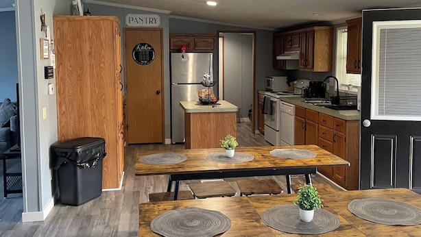 A modern kitchen with wooden cabinets, a stainless steel refrigerator, and a dining area with a wooden table and chairs. - Quite, private 4 bed room 2 full bath home located in Newark oh. Sleeps 12. (Heath)