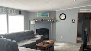 A living room with a gray sofa, a coffee table, a fireplace, and a television. - Quite, private 4 bed room 2 full bath home located in Newark oh. Sleeps 12. (Heath)