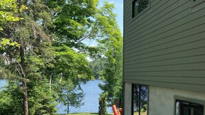 A landscaped patio with stone tiles, a small garden with mulch and plants, and a view of a lake. - Luxury Lakefront Retreat | 3 bed,3 bath, near Parry Sound | Save on Weekly Stays (Parry Sound)
