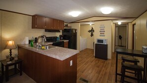 Una cocina compacta con armarios de madera, una isla central, un fregadero y un microondas.