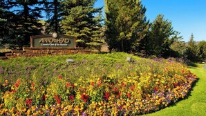 A sign for Arrowhead Country Club of the Rockies surrounded by a vibrant flower garden.