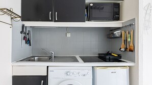 Pieni, käytännöllinen keittiö, jossa on pesuallas, mikroaaltouuni, astianpesukone ja pieni jääkaappi.