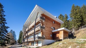 A modern multi-story building with a wooden facade, large windows, and a balcony on the upper floor. - Near the slopes, nice Appt for 6 pers (Chamrousse)