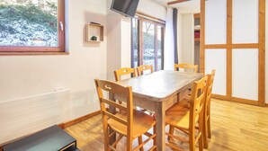 A dining area with a wooden table and chairs, a window with a view of a snowy landscape, and a television mounted on the wall. - Near the slopes, nice Appt for 6 pers (Chamrousse)