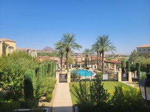 Un complexe hôtelier doté d’une piscine, de palmiers et offrant une vue sur des bâtiments et des montagnes situés au loin.