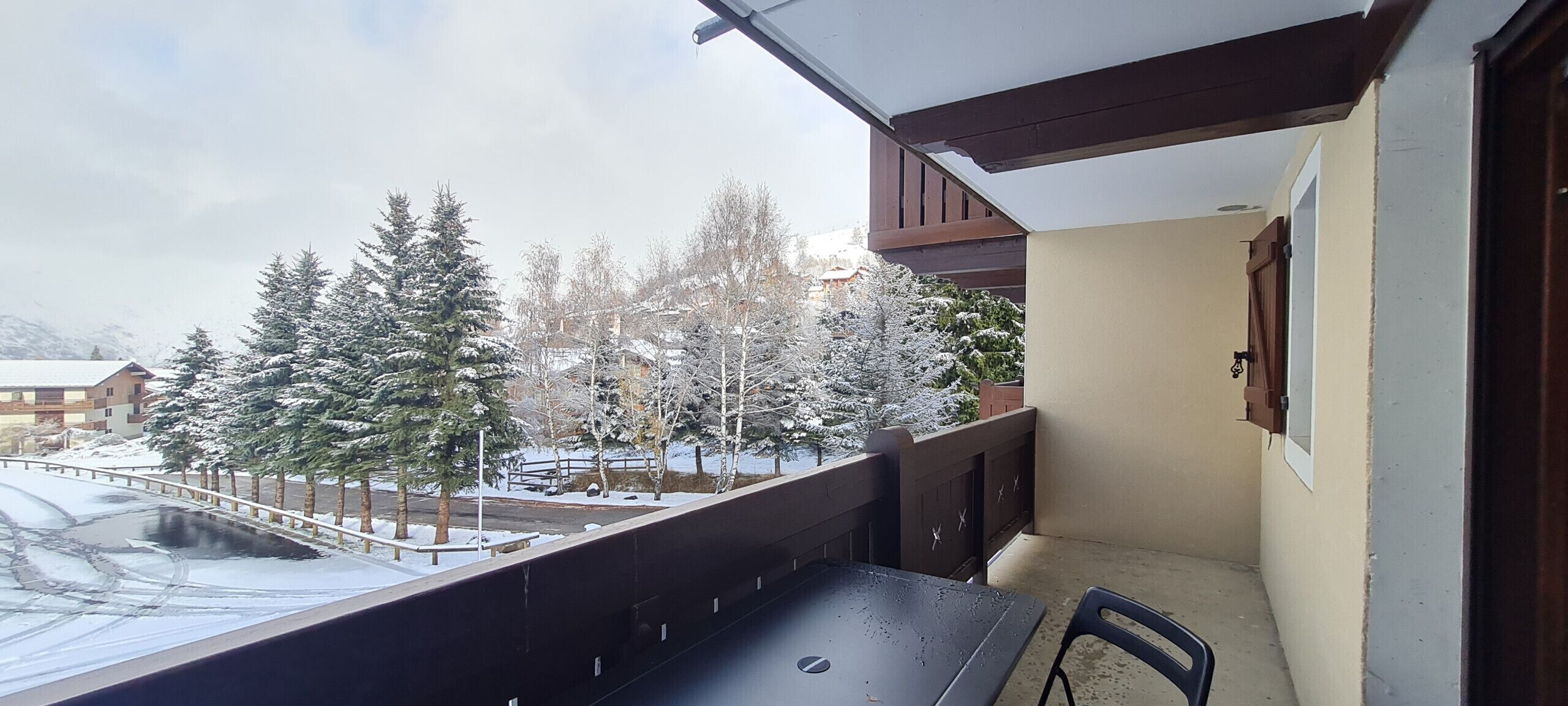 A balcony with a view of snow-covered trees and buildings.