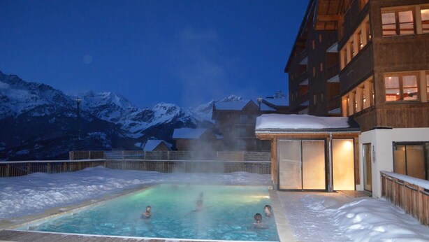 A hot tub with people in it, surrounded by snow and mountains in the background. - Flat at the foot of the slopes with a balcony (Modane)