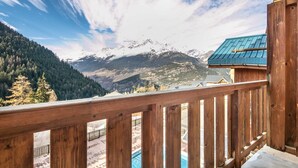 A wooden balcony with a view of snow-capped mountains and a forested valley. - Flat at the foot of the slopes with a balcony (Modane)