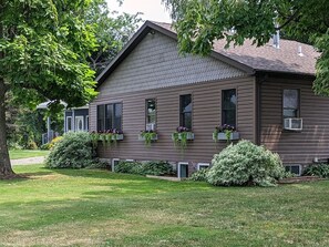 A two-story house with a sloped roof, multiple windows, and a front porch with flower boxes.