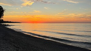 Una playa de piedras con un atardecer sobre el agua.
