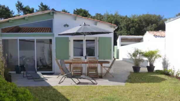 Une terrasse avec une table et des chaises, un espace abrité et une porte-fenêtre coulissante donnant sur une pièce.
