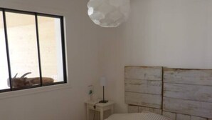 Une chambre à coucher avec un lit, une fenêtre, une lampe et une tête de lit en bois.