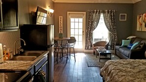 A compact living space with a kitchenette, a dining area, a sofa, and a bed.