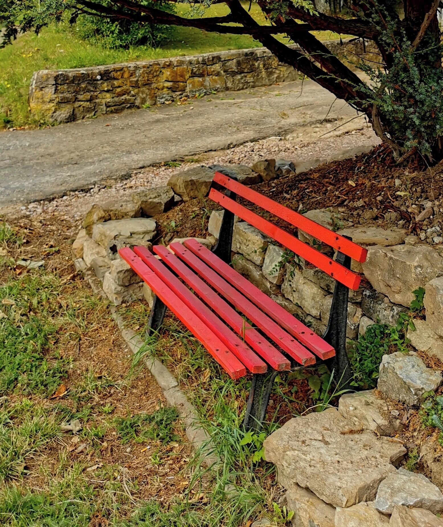 Eine rote Bank vor einer Steinmauer.