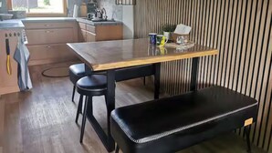 Una cocina moderna con una mesa de madera, taburetes negros y un banco.
