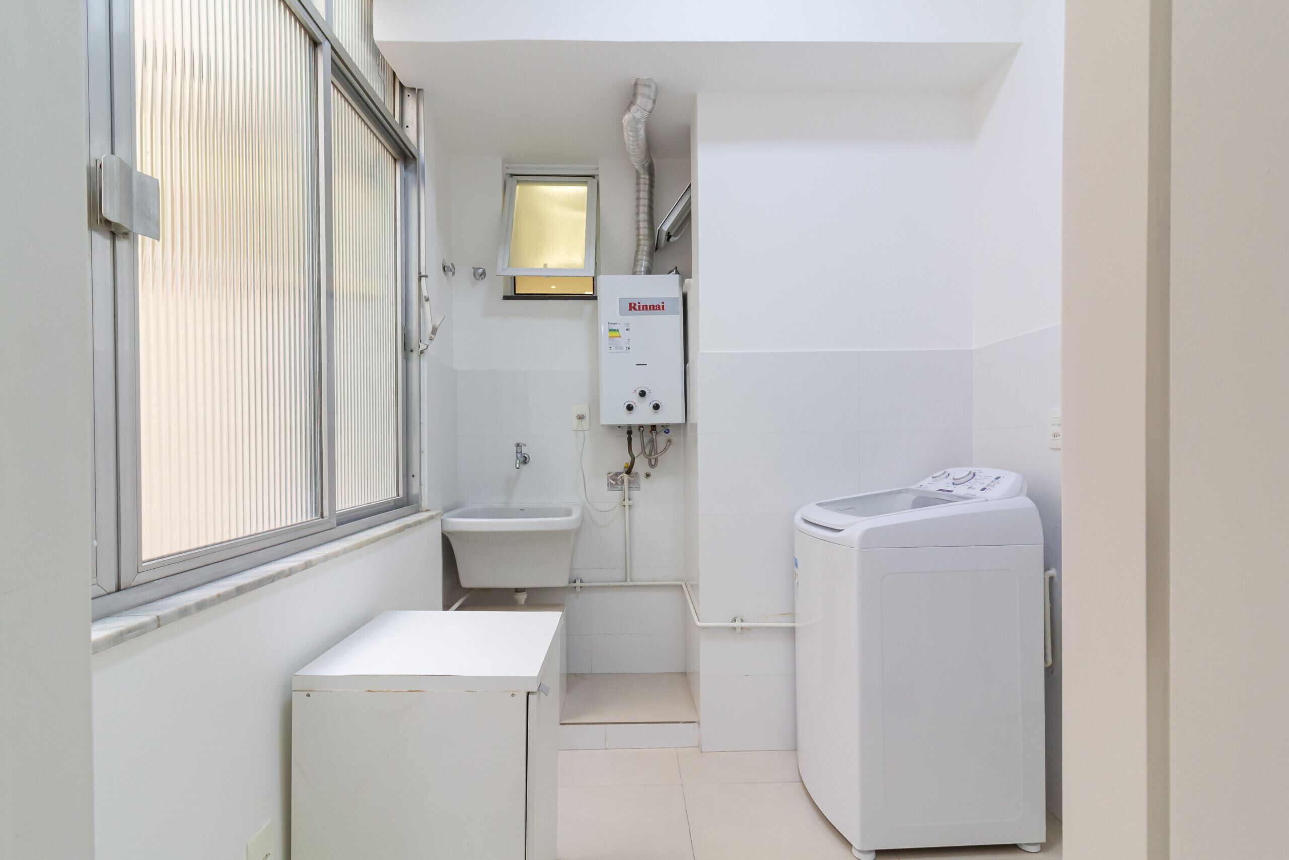 Une petite salle de bain avec une fenêtre, un lavabo, des toilettes et un lave-linge.