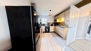 Une cuisine équipée d’un lave-linge, de meubles en bois et d’un réfrigérateur.