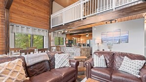 A spacious living area with a brown leather sofa, a wooden coffee table, and a stone fireplace. - Secluded Cabin for 10, Near Pkwy (Pigeon Forge)
