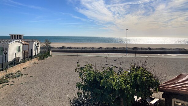 A beach view with a clear sky, a sandy beach, and a row of small houses with a fence. - Vacation home 30 metres from the beach (Fleury)