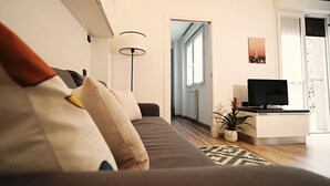 A modern living room with a sofa, a TV, a lamp, and a potted plant. - Modern Apt Next to M3 Metro, Milan (Milan)