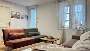 A cozy living room with a brown sofa, a green sofa, a small wooden table, and a bed with a white blanket. - Maison Auseths - Group accommodation - Campan (Campan)