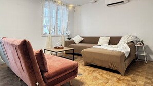 A living room with a brown sofa, a pink armchair, a small table, and a window with sheer curtains. - Maison Auseths - Group accommodation - Campan (Campan)