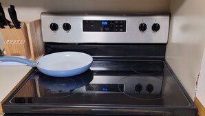Una cocina con estufa, sartén y un reloj que marca las 8:28.