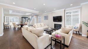 A spacious living room with a large sofa set, a coffee table, and a fireplace. There is a dining area with a table and chairs, and a staircase leading to another level. - Spacious & Modern Home in The Heart of Toronto (Toronto)