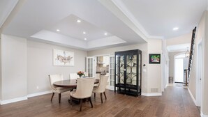A spacious dining area with a round table and chairs, a black cabinet with glass doors, and a kitchen in the background. - Spacious & Modern Home in The Heart of Toronto (Toronto)