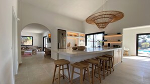Una cucina moderna con una grande isola, sgabelli da bar e un lampadario a sospensione.