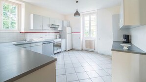 A modern kitchen with white cabinets, a built-in oven, and a large window. - Charming cottage (Aldudes)