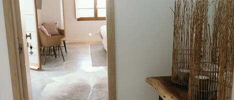 Una habitación con puerta de madera, el número 6 en la pared, un espejo y una mesa con ramas decorativas.