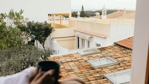 Una persona sentada junto a una ventana con vista a un patio con edificios y árboles.