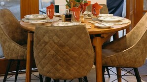 Un comedor con una mesa de madera dispuesta para cuatro personas, rodeada de sillas acolchadas.