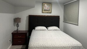 Un dormitorio con una cama, una mesita de noche, una lámpara y un cuadro en la pared.