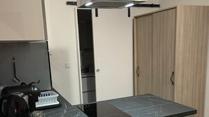 Een moderne keuken met een zwart marmeren aanrechtblad, een roestvrijstalen afzuigkap en inbouwapparatuur.