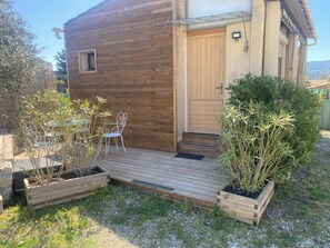 Una cabaña de madera con un porche de madera, una puerta y un ventanal pequeño.