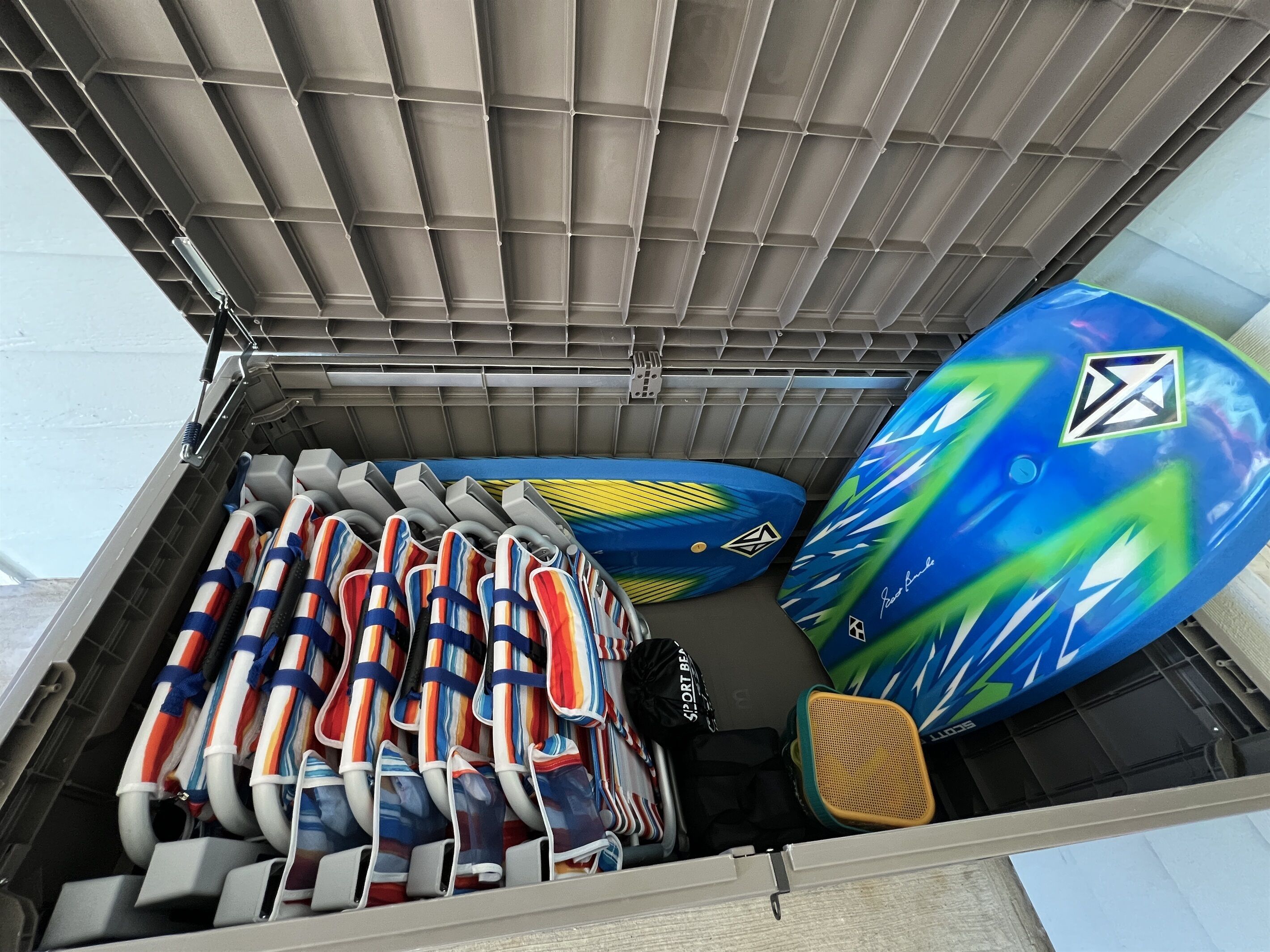 Un espace de rangement où les gilets de sauvetage sont rangés de manière ordonnée, ainsi qu’une planche de surf aux couleurs vives.