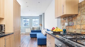 Eine moderne Küche mit Holzausstattung, einem Herd und einem Essbereich mit einem blauen Sofa und einer Obstschale.
