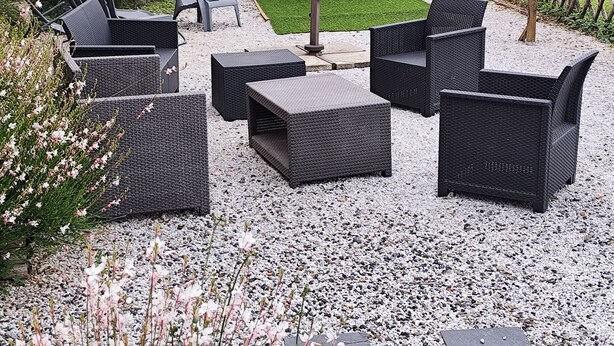 Een terras buiten met rieten meubilair, een jacuzzi en een houten pergola.
