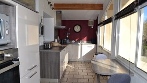 Een kleine keuken met een inbouwoven, een koffieapparaat en een klok aan de muur.