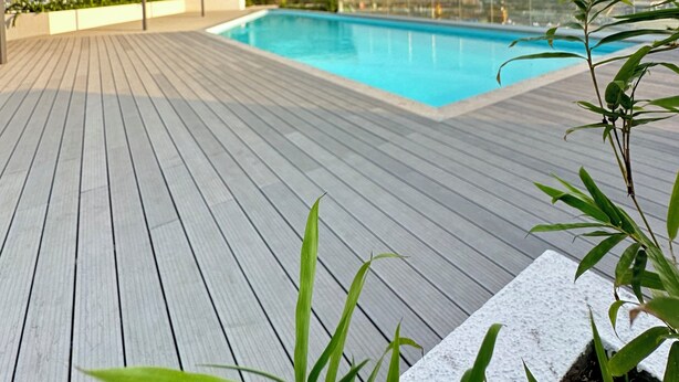 A rooftop pool with a wooden deck and a stone structure in the background. - Loxwood Apartment (Accra)