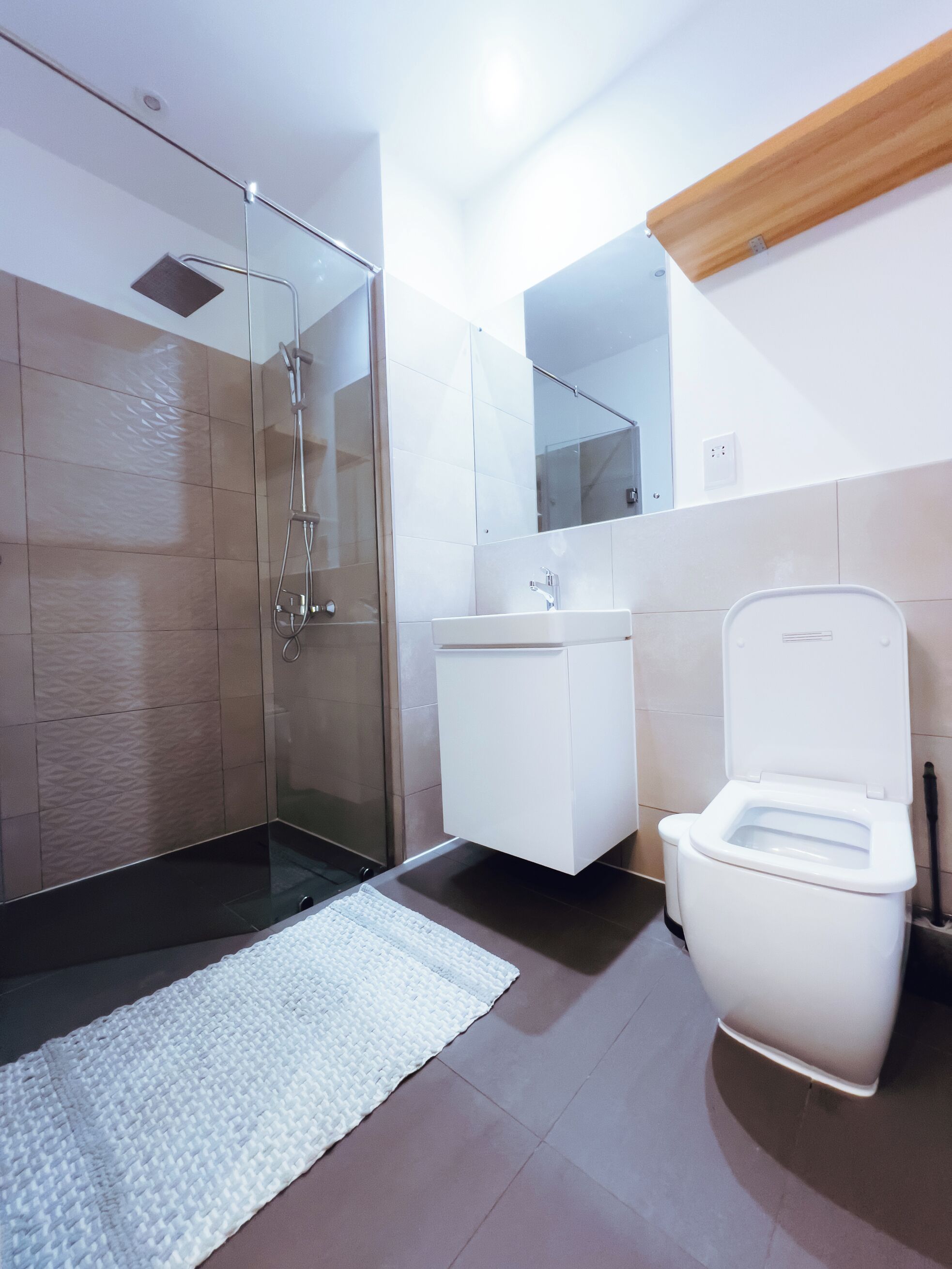 Ein modernes Badezimmer mit einer Duschkabine aus Glas, einem weißen Waschbecken und einer Toilette.